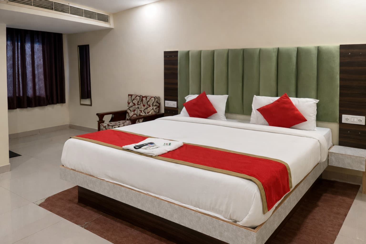 Deluxe room with green velvet headboard and red accents